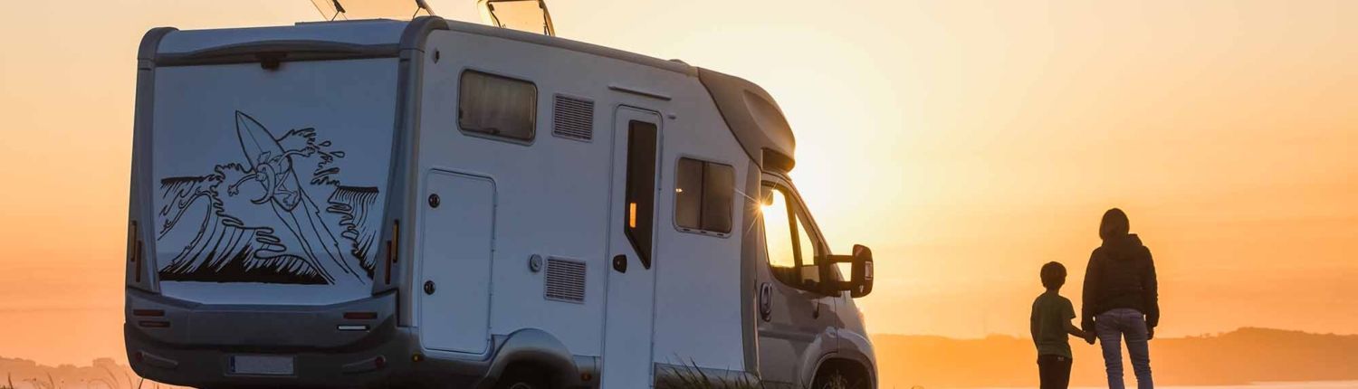 mother and son watching the sunset with their motor home at the edge of the sea mother and son watching the sunset with their motor home at the edge of the sea