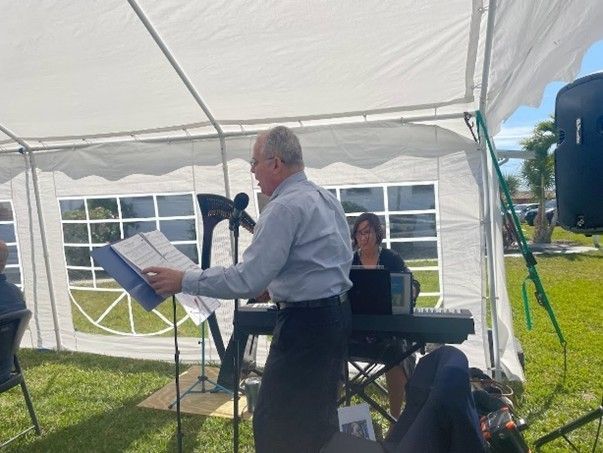 A man is standing in front of a white tent holding a piece of paper.