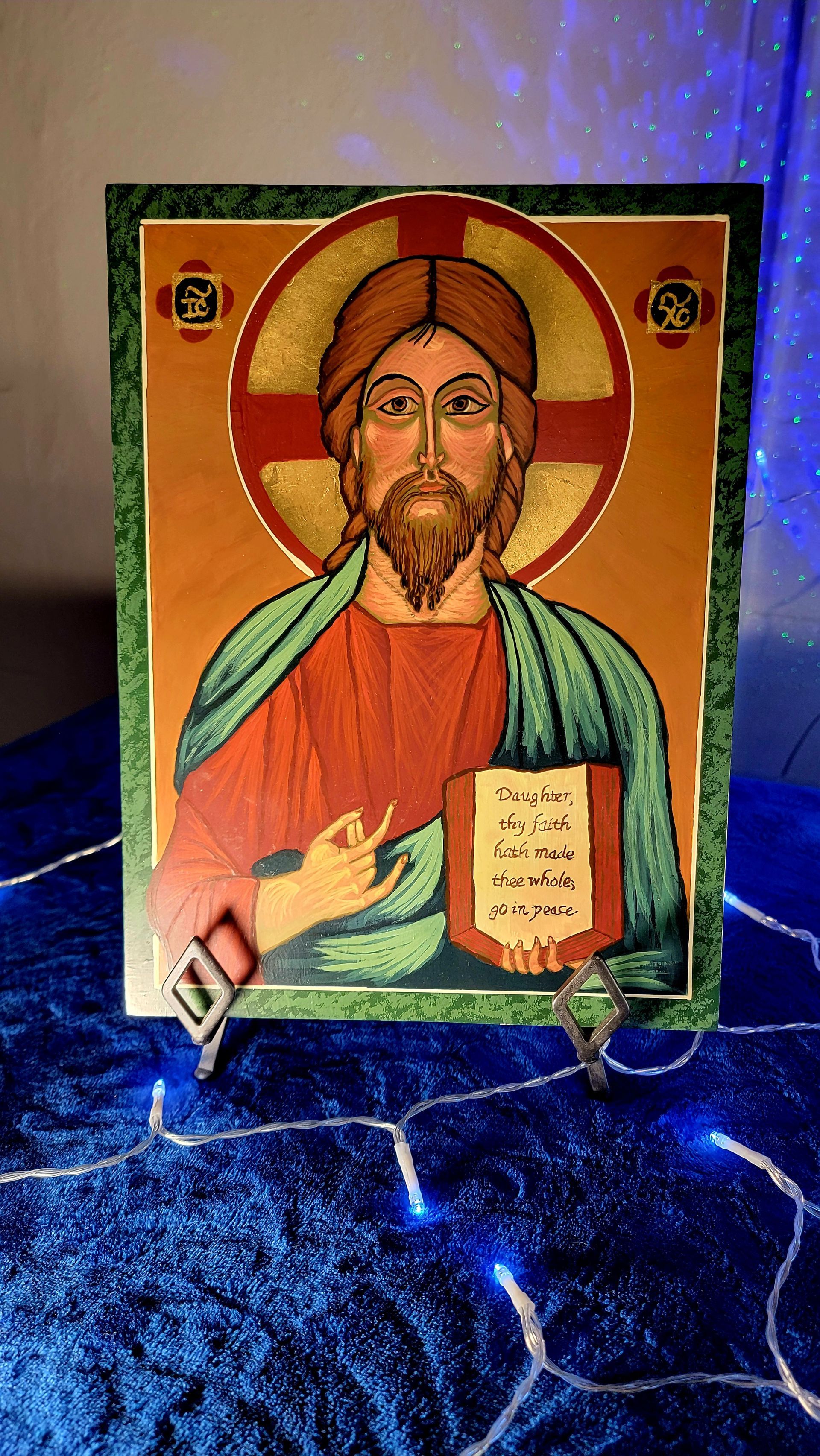 Icon of Jesus Christ, haloed, holding a book. Gold, red, green, and tan colors. Set against a dark blue background.