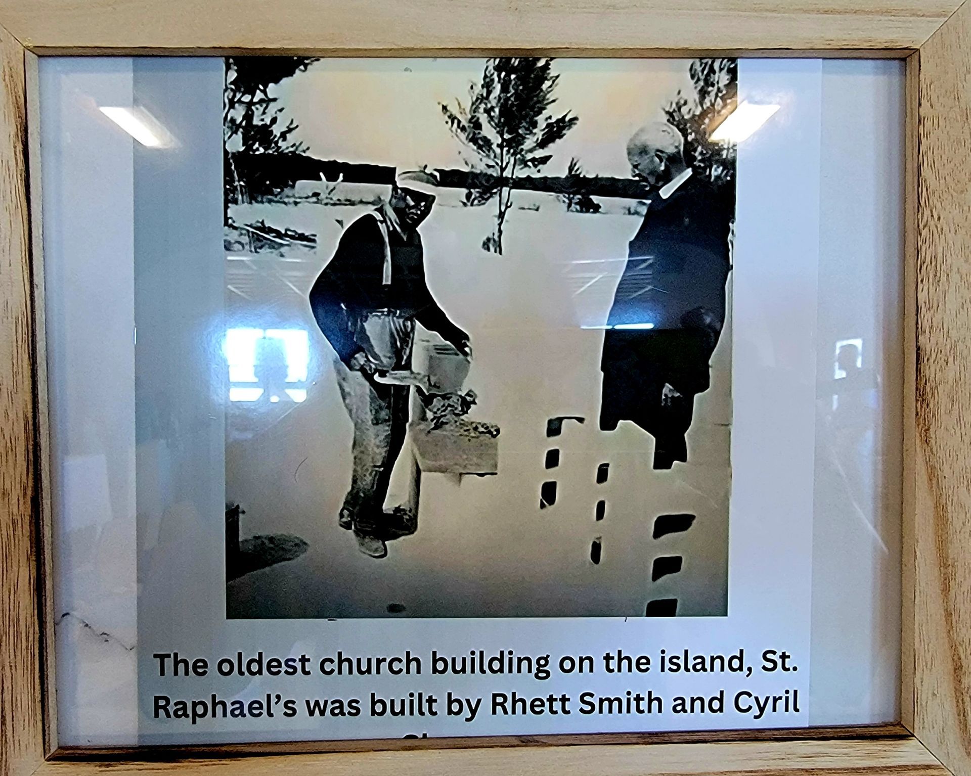 Black and white photo of two men building a church. Text reads 