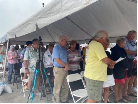A group of people standing under a white tent
