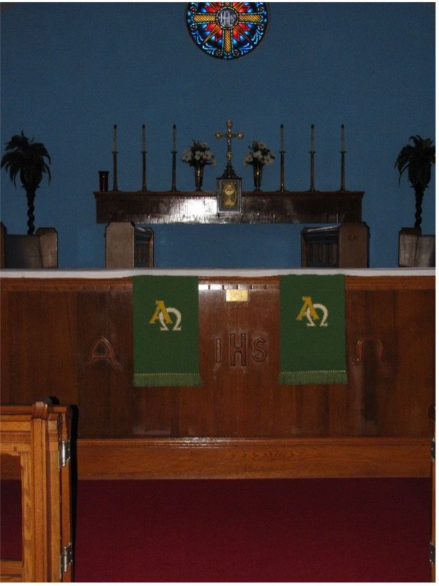 A church altar with a green cloth with the letters a and o on it