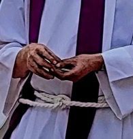 A man wearing a robe and tie is holding a rope around his waist.