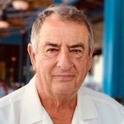 A man in a white shirt is looking at the camera.