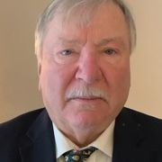 A man with a mustache is wearing a suit and tie.