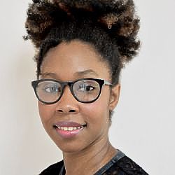 A woman wearing glasses and a black shirt is smiling for the camera.