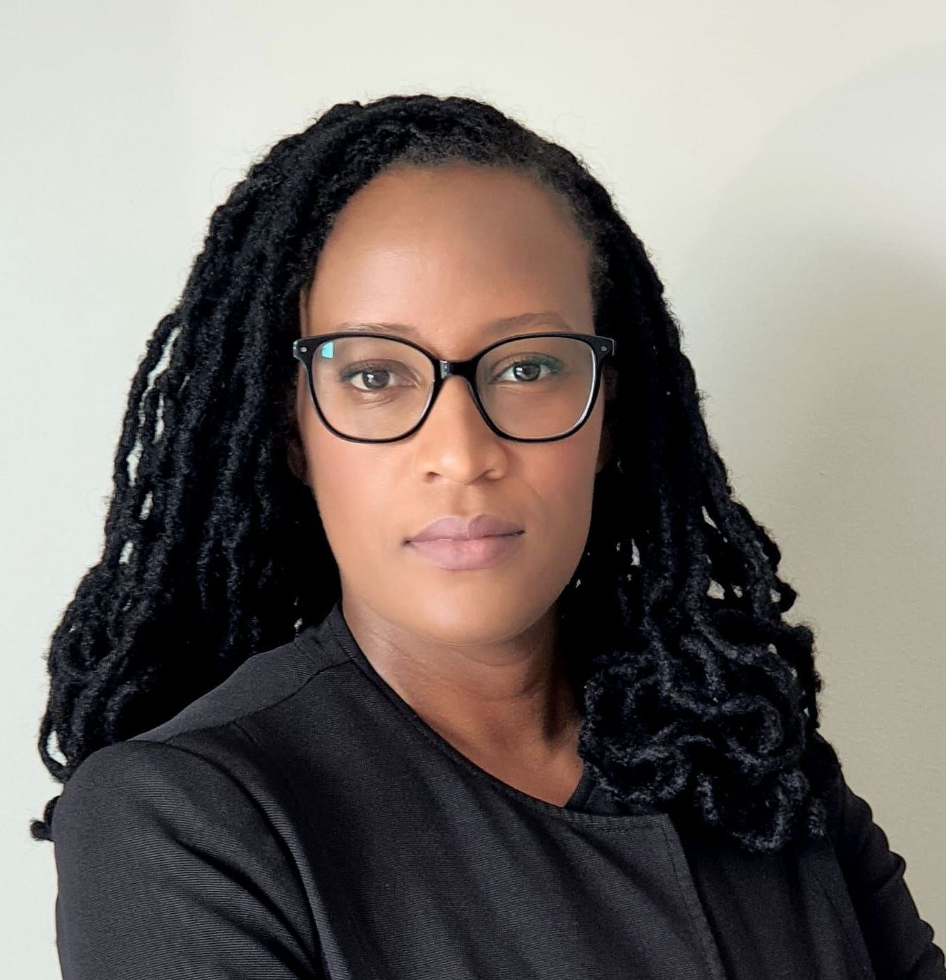 A woman with dreadlocks wearing glasses and a black jacket