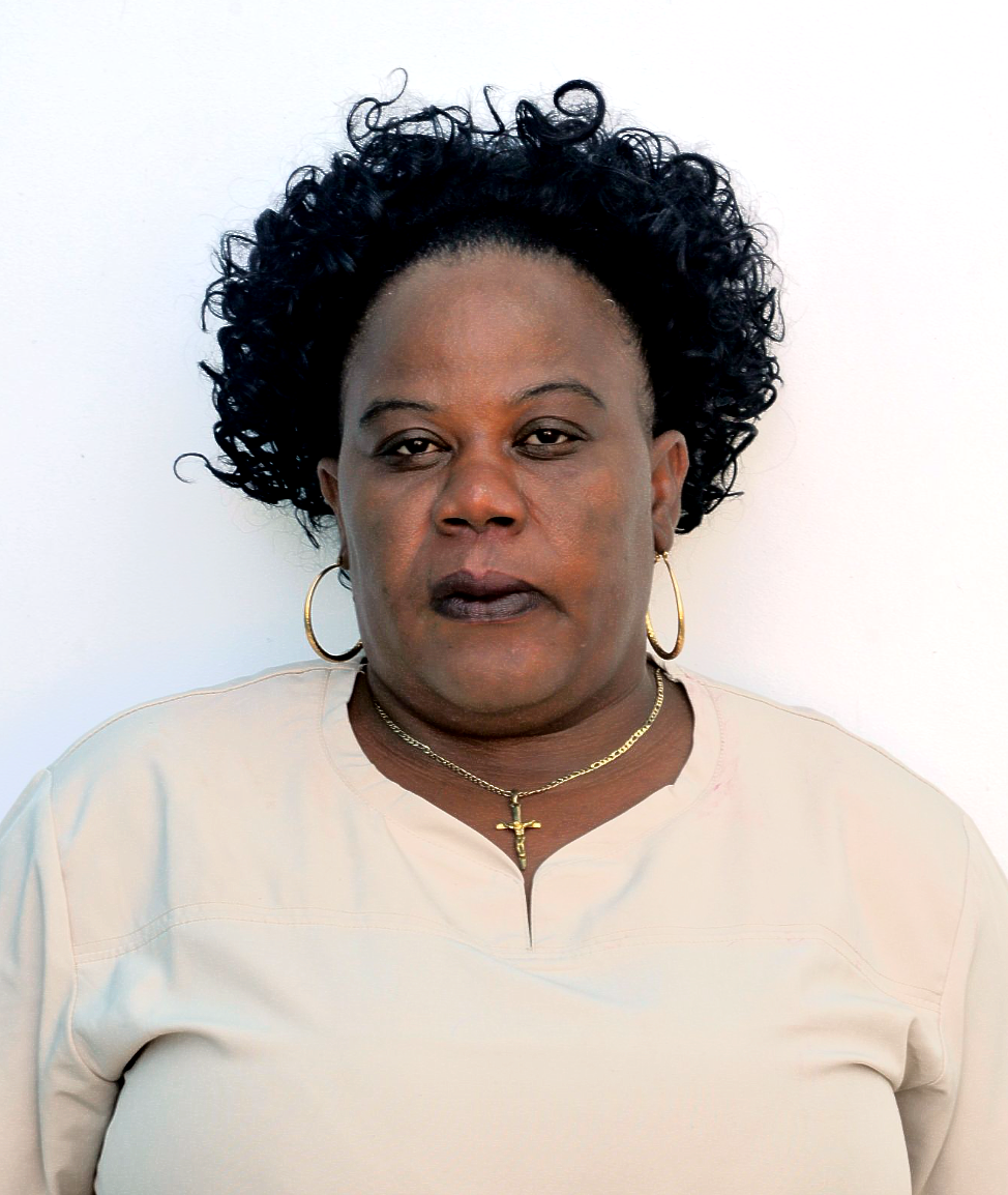 A woman with curly hair is wearing a necklace and earrings