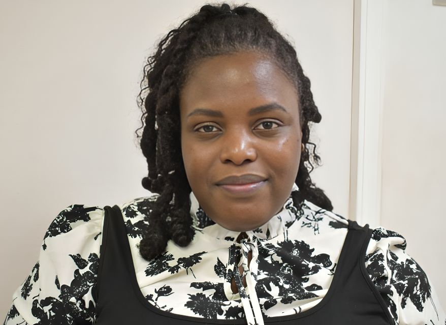 A woman with dreadlocks is wearing a black and white floral shirt.