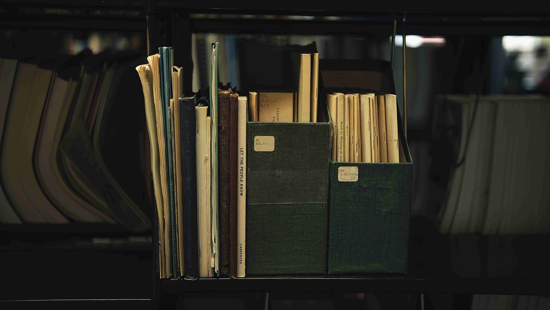 A stack of books sitting on top of a shelf in a library.