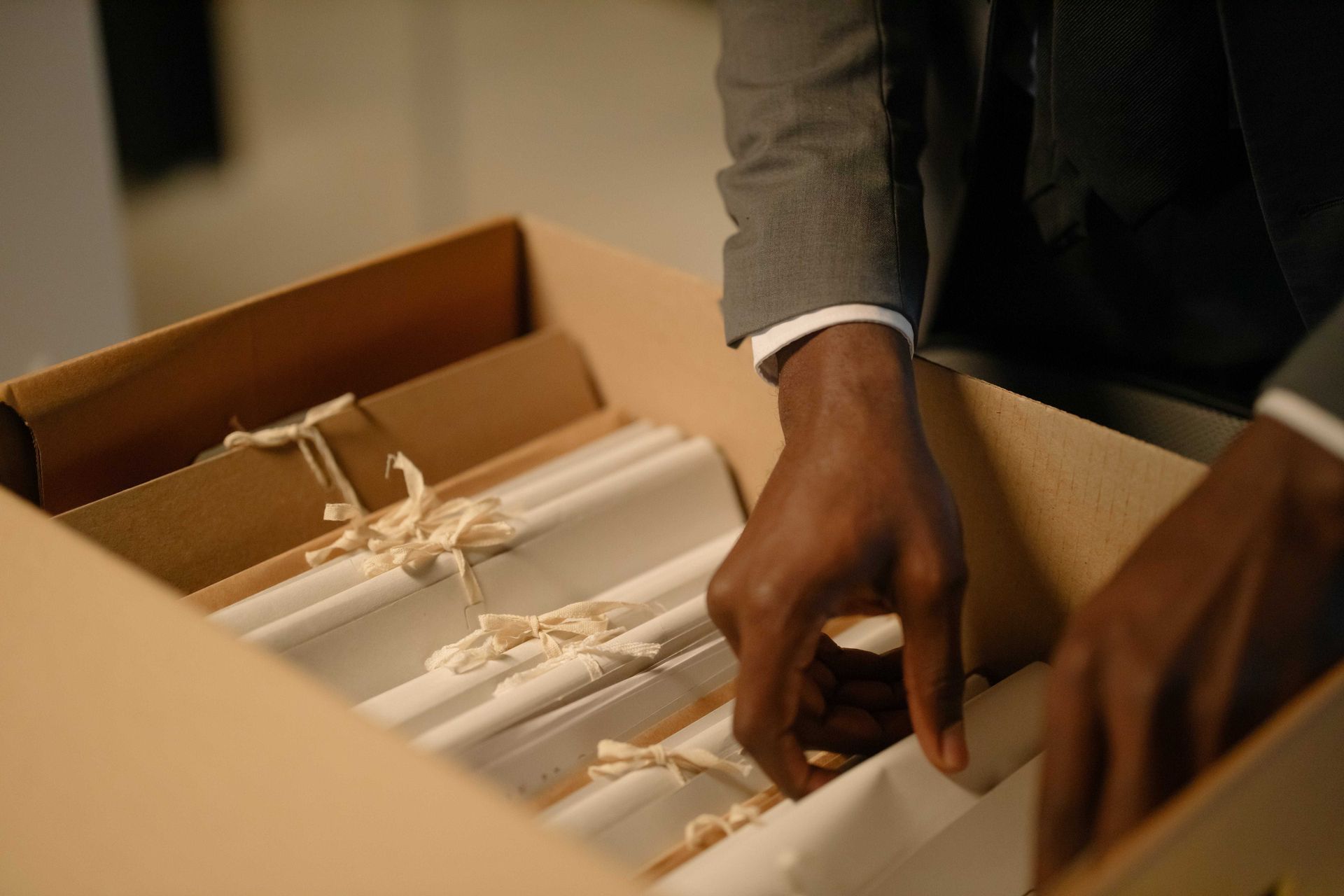 A man in a suit is opening a box of blinds.