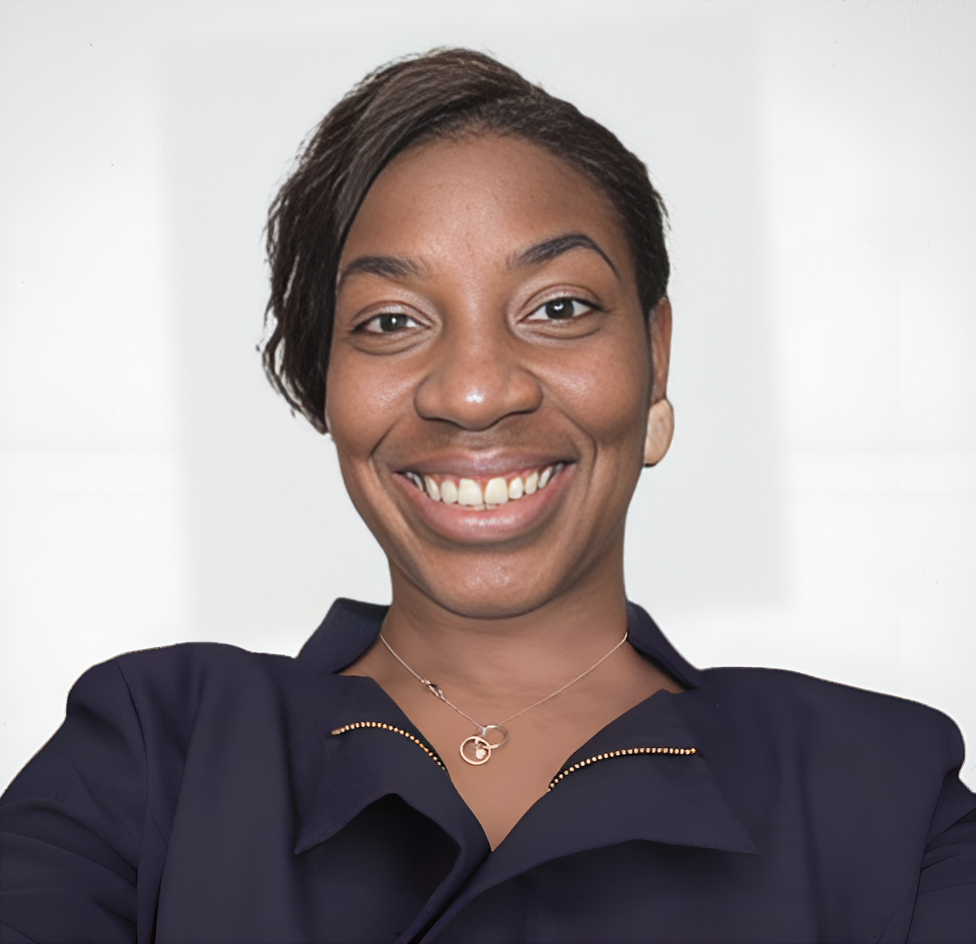 A woman wearing a blue jacket and a necklace smiles for the camera