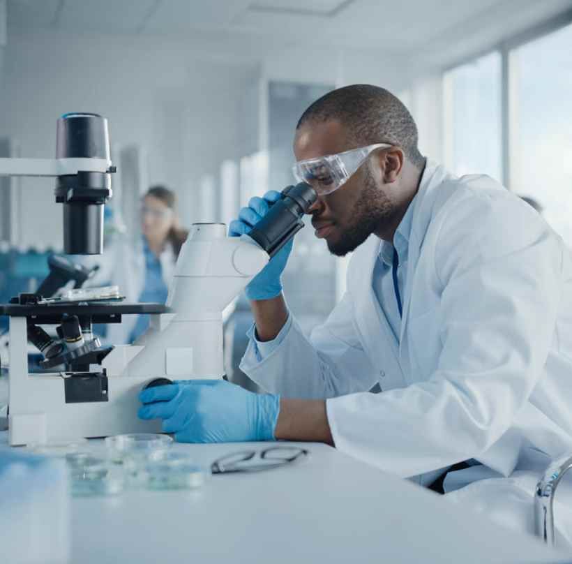 A scientist is looking through a microscope in a laboratory.