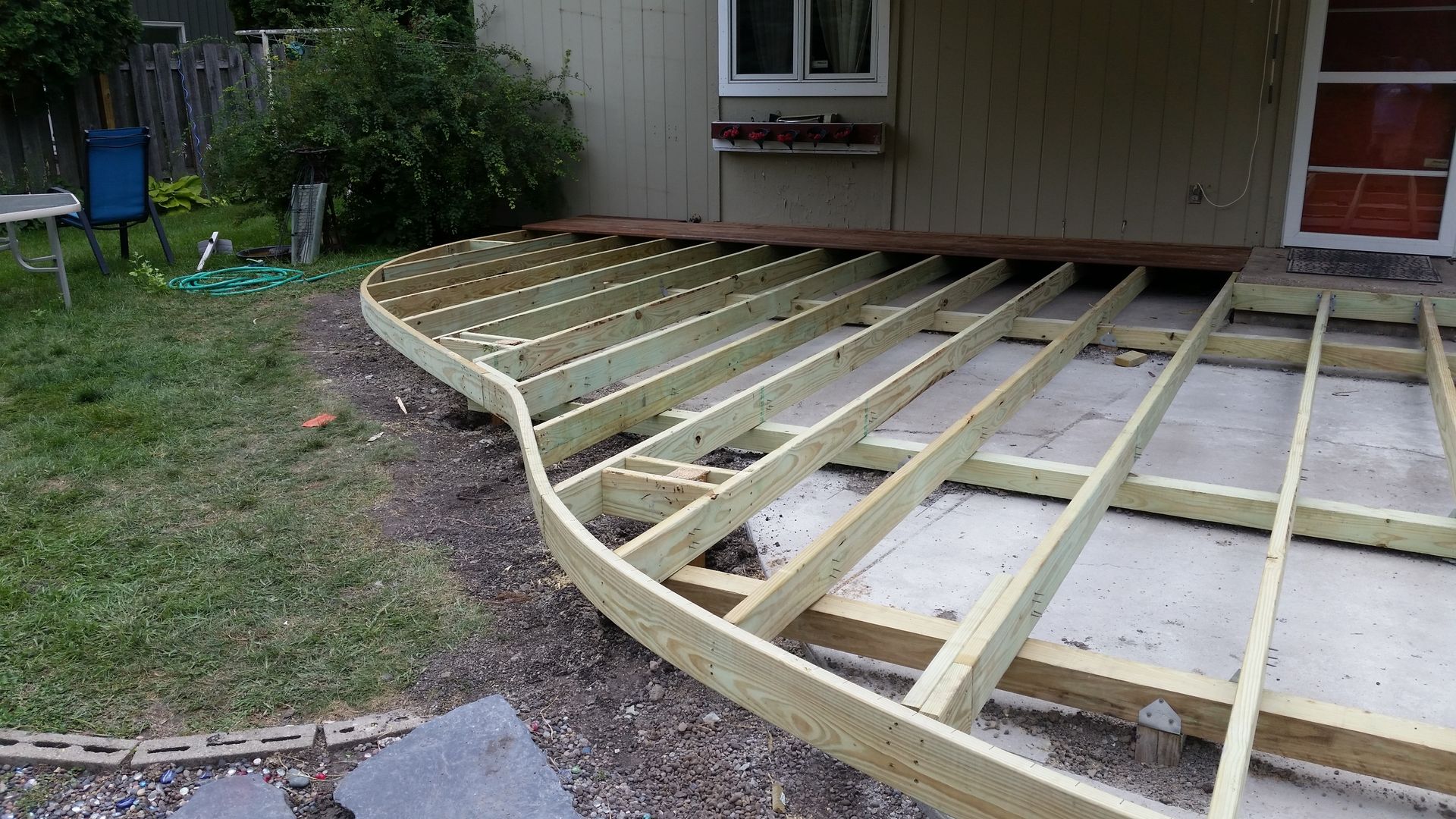 A wooden deck is being built in the backyard of a house.