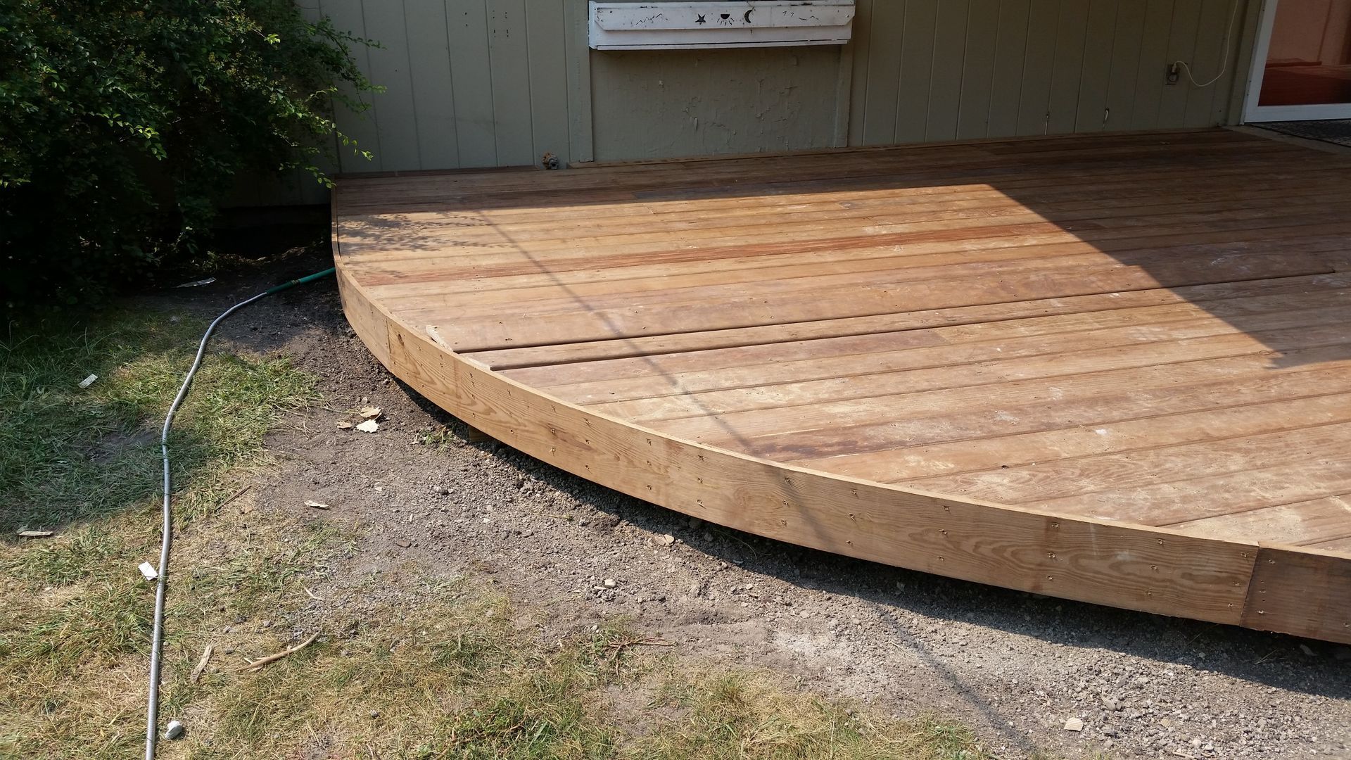A wooden deck is being built in the backyard of a house.