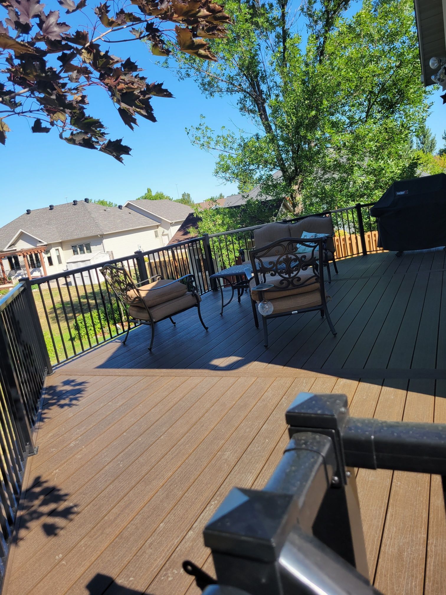 A deck with furniture and a grill on a sunny day