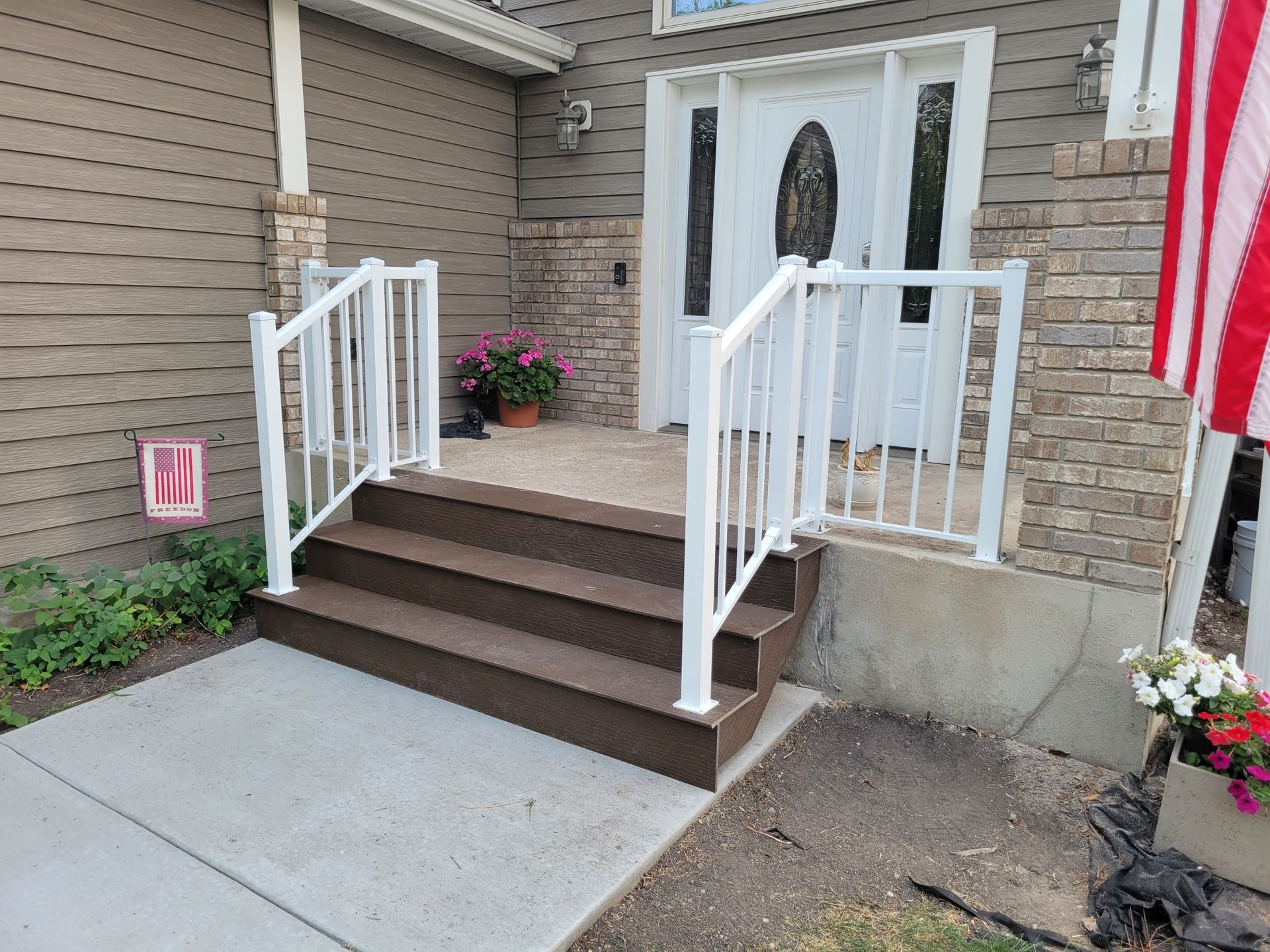 A front porch with stairs and a white railing
