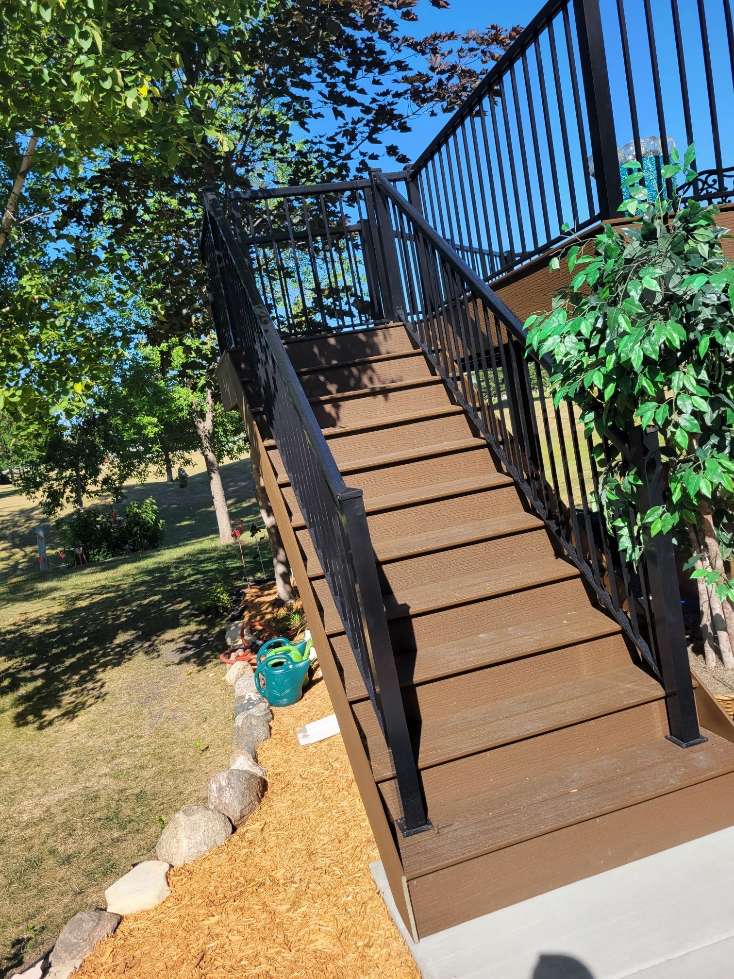 A set of stairs leading up to a deck with a black railing.