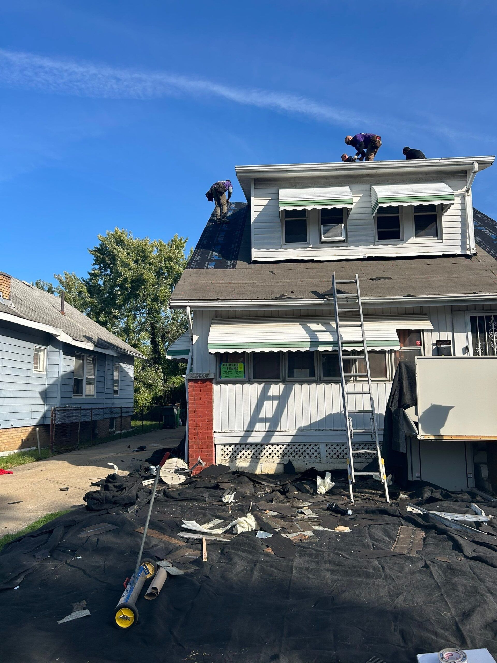 Fire-damaged house with collapsed porch, charred debris, and smoke stains under a blue sky