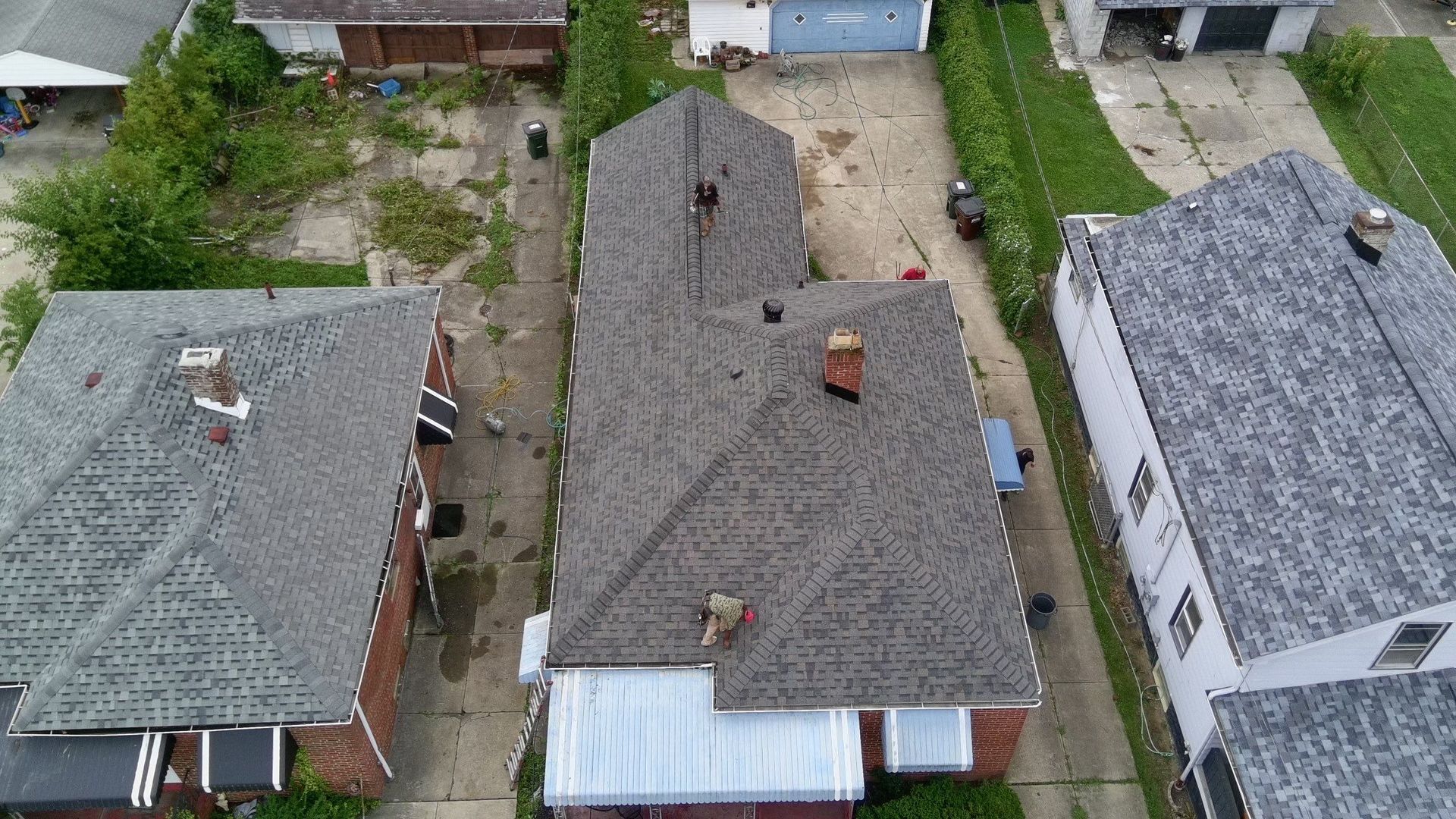 Aerial view of three neighboring houses with gray roofs, driveways, and small yards.