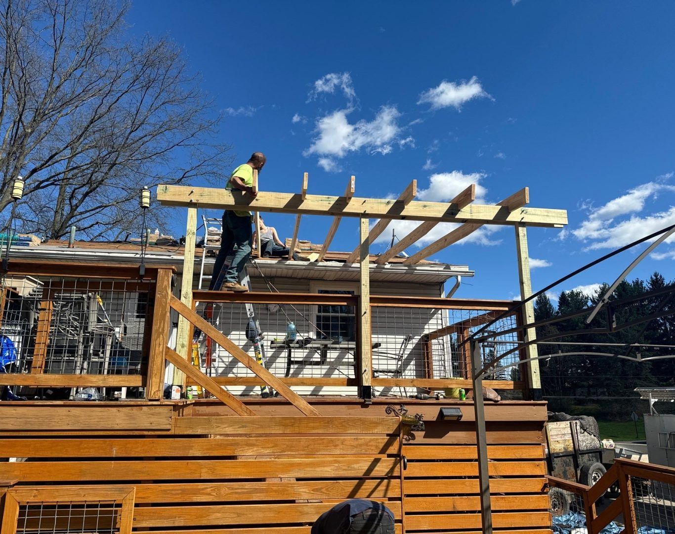 Worker installing roof beams on a wooden house under construction outdoors