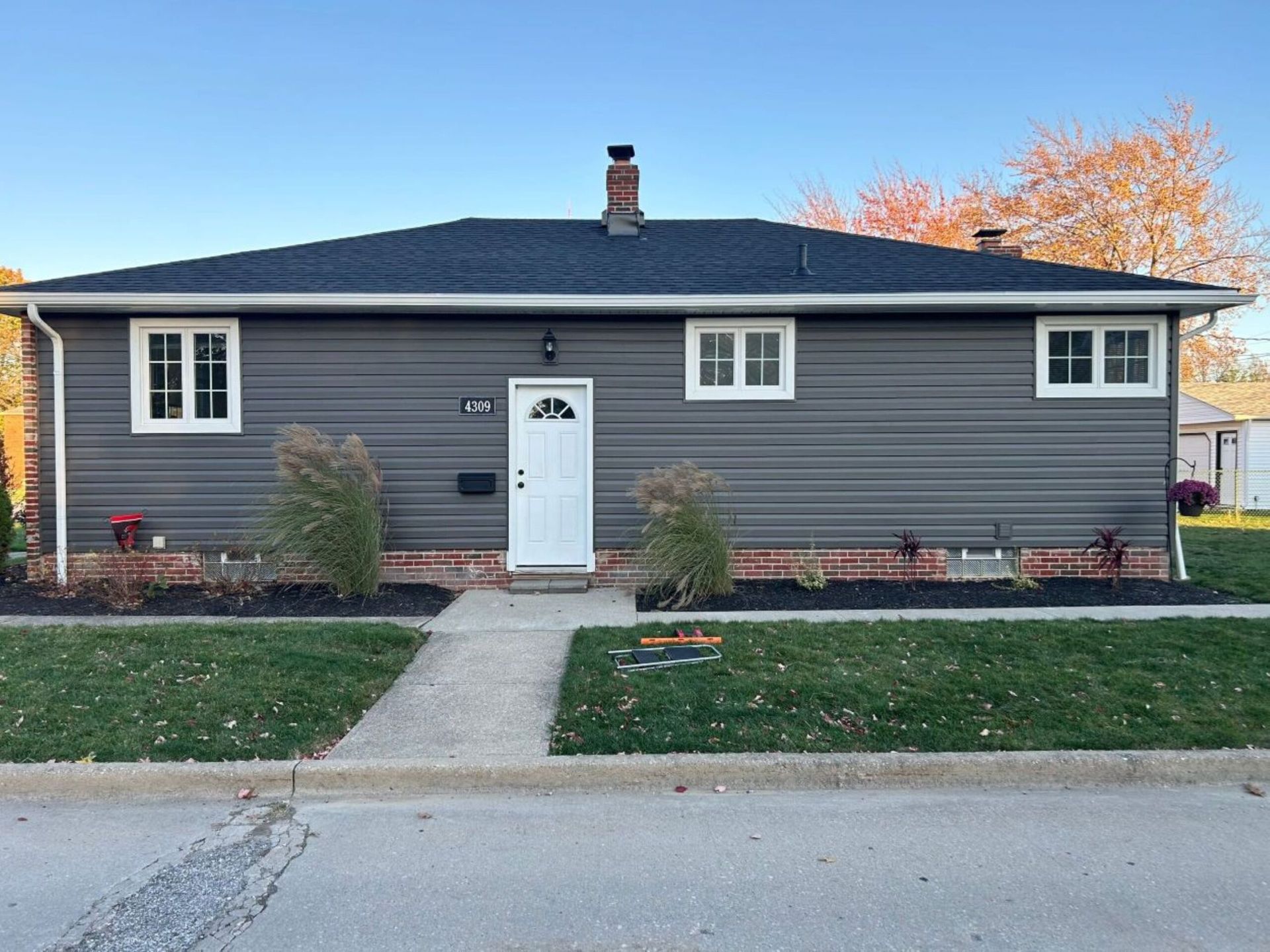 Single-story gray house with white trim, centered front door, and a walkway to the street.