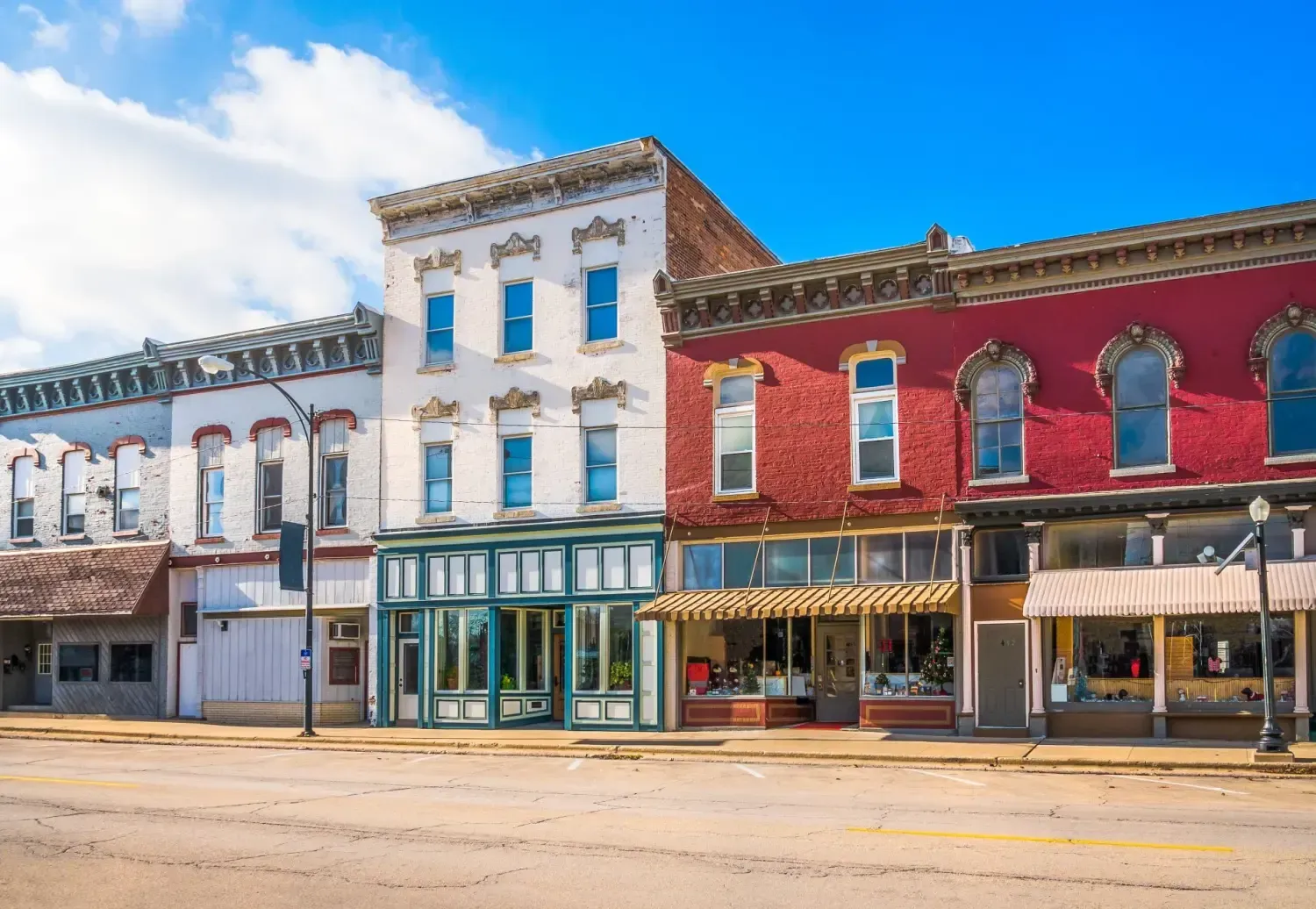 Colorful historic storefronts on a sunny downtown street with brick and painted facades