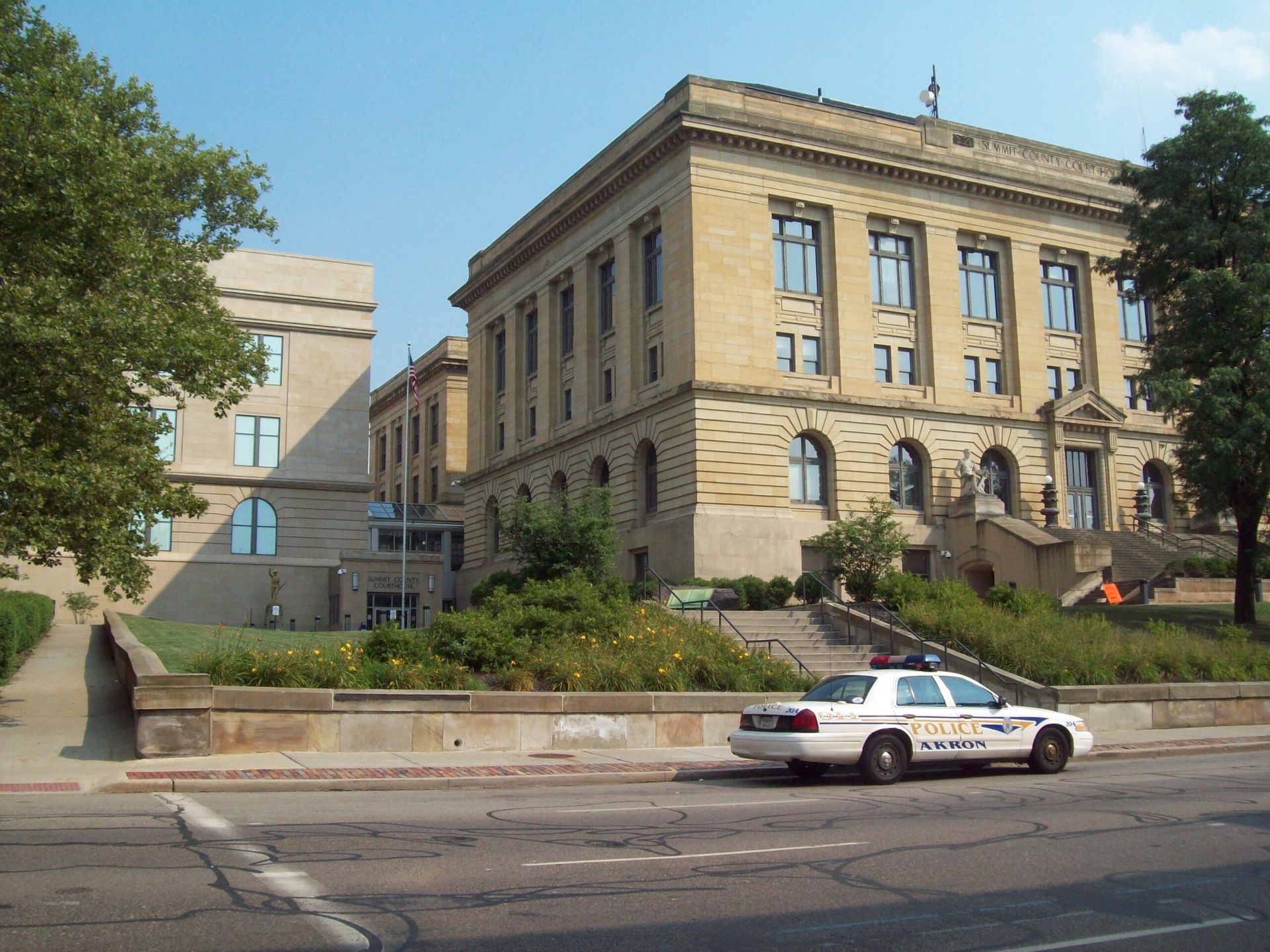 Historic stone building with a police car parked on the street in front, under a clear sky