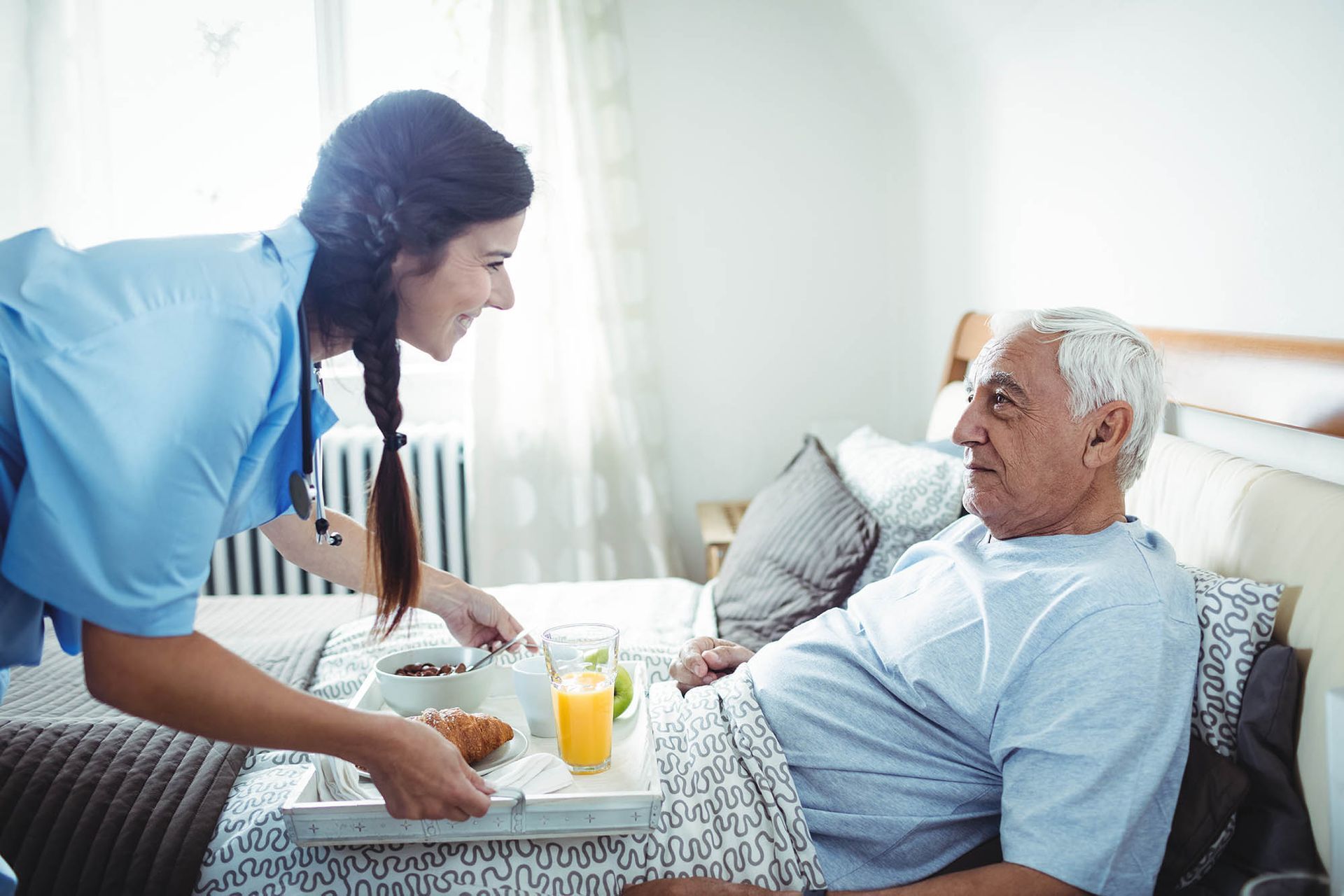 A caregiver is serving breakfast to a senior man.