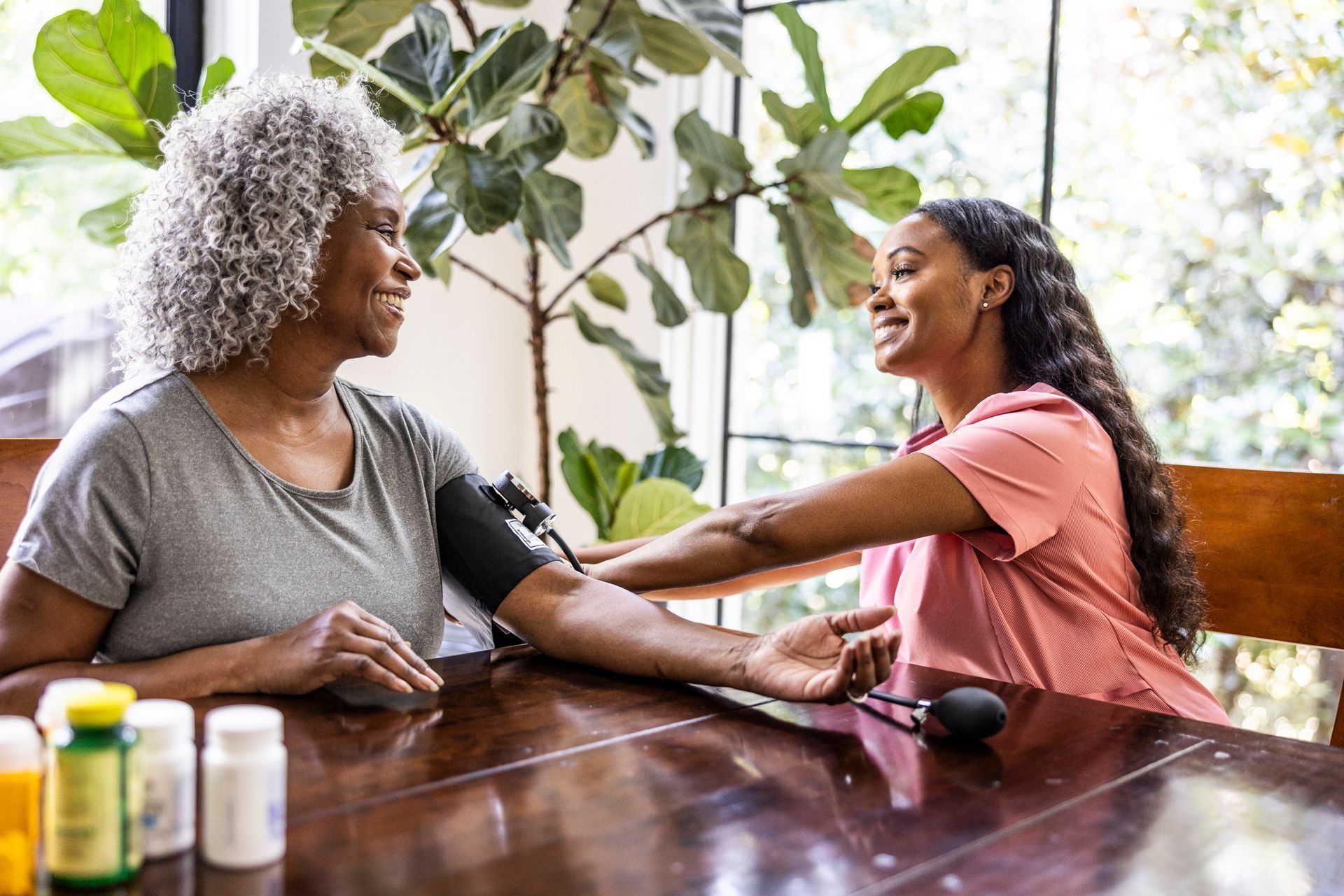 Home care services provider measuring senior woman's blood pressure in her home.