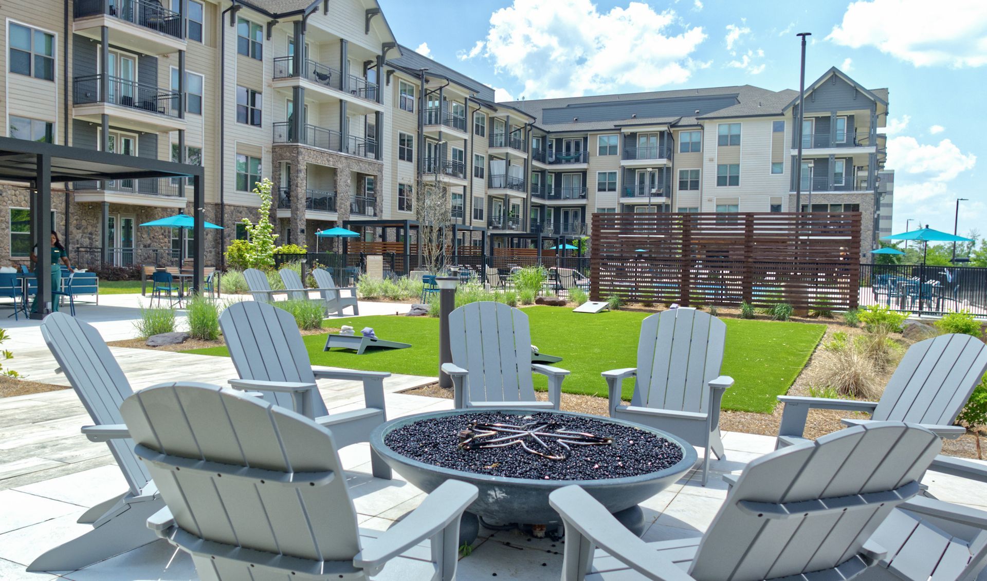 Apartment courtyard with white Adirondack chairs around a fire pit on a sunny day