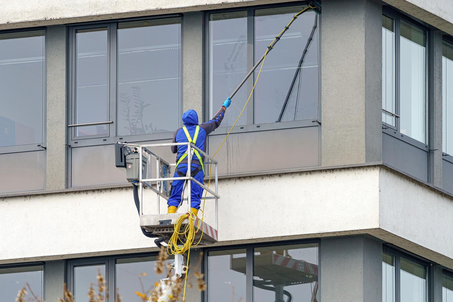 Window cleaner in a lift washing an office building window.