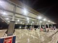 Gas station at night, illuminated by overhead lights, fuel pumps, 