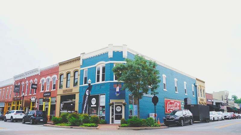 Buildings on a downtown street, including a blue corner building with a Coca-Cola sign.