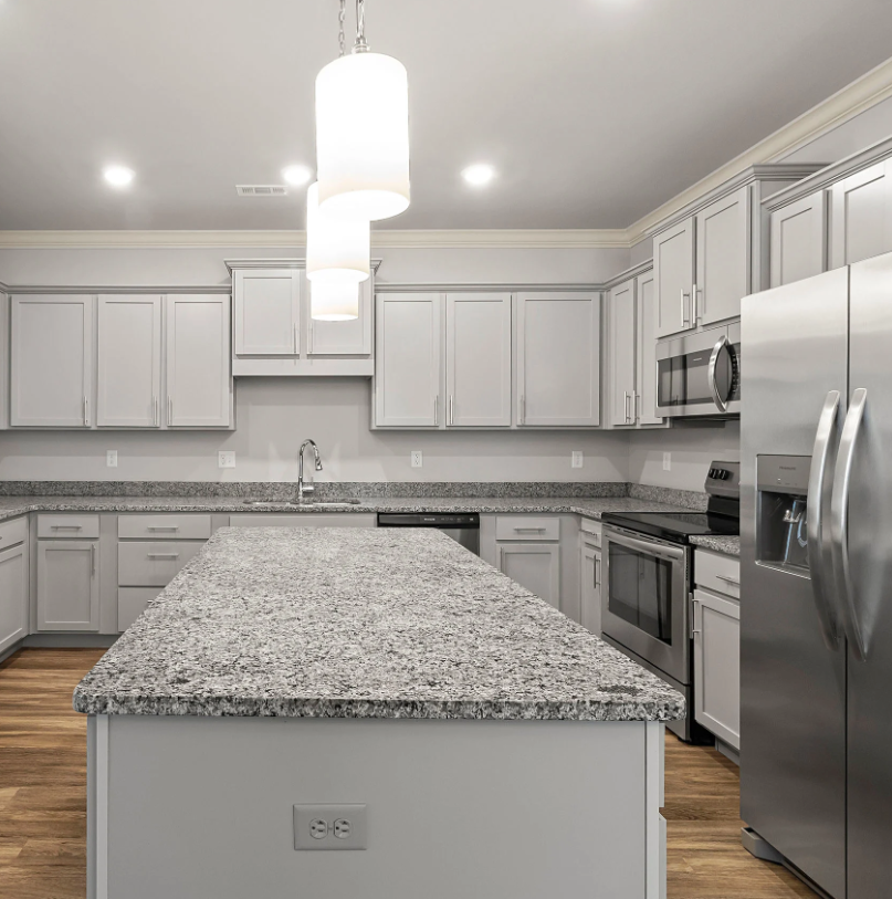 Modern kitchen with light gray cabinets, granite countertops, and stainless steel appliances.