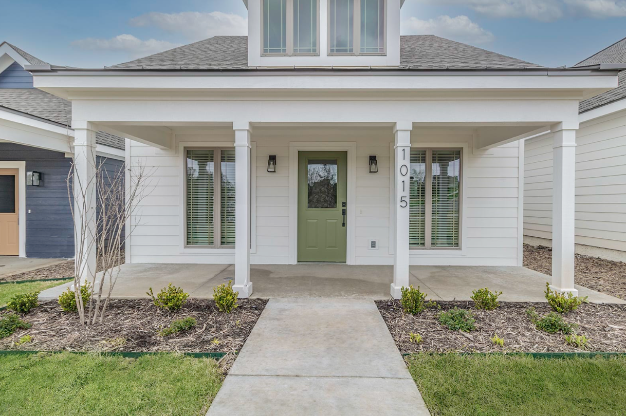 White house with green door, covered porch, and address 