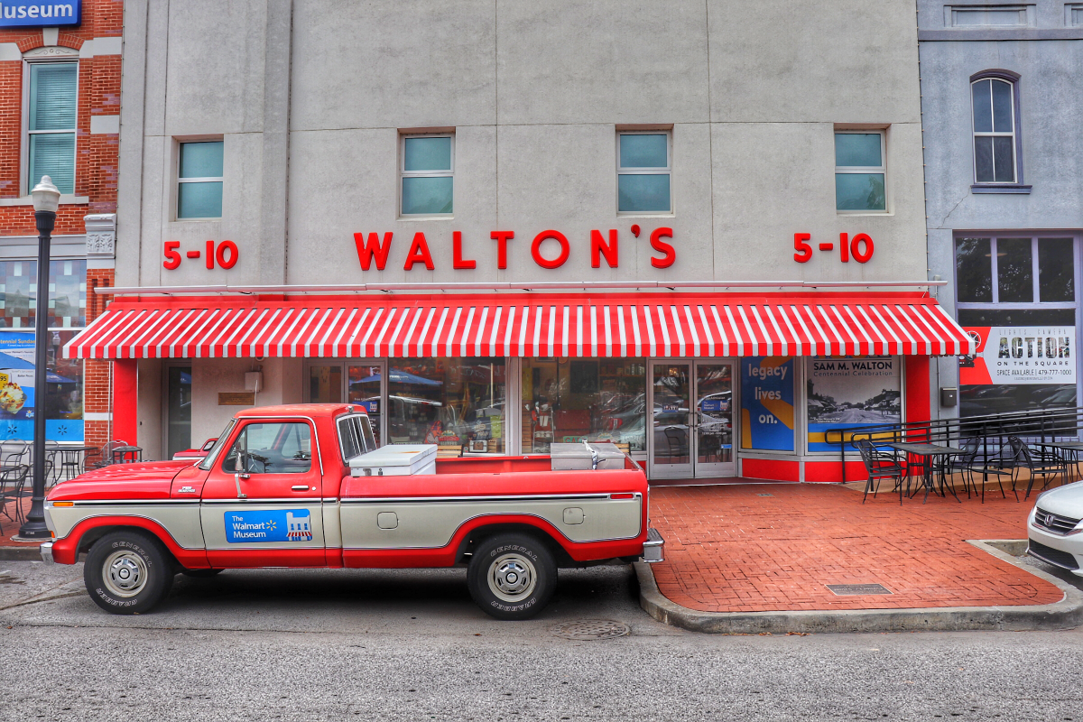 Red and white Walton's 5-10 store with red awning and a red and white pickup truck parked in front.