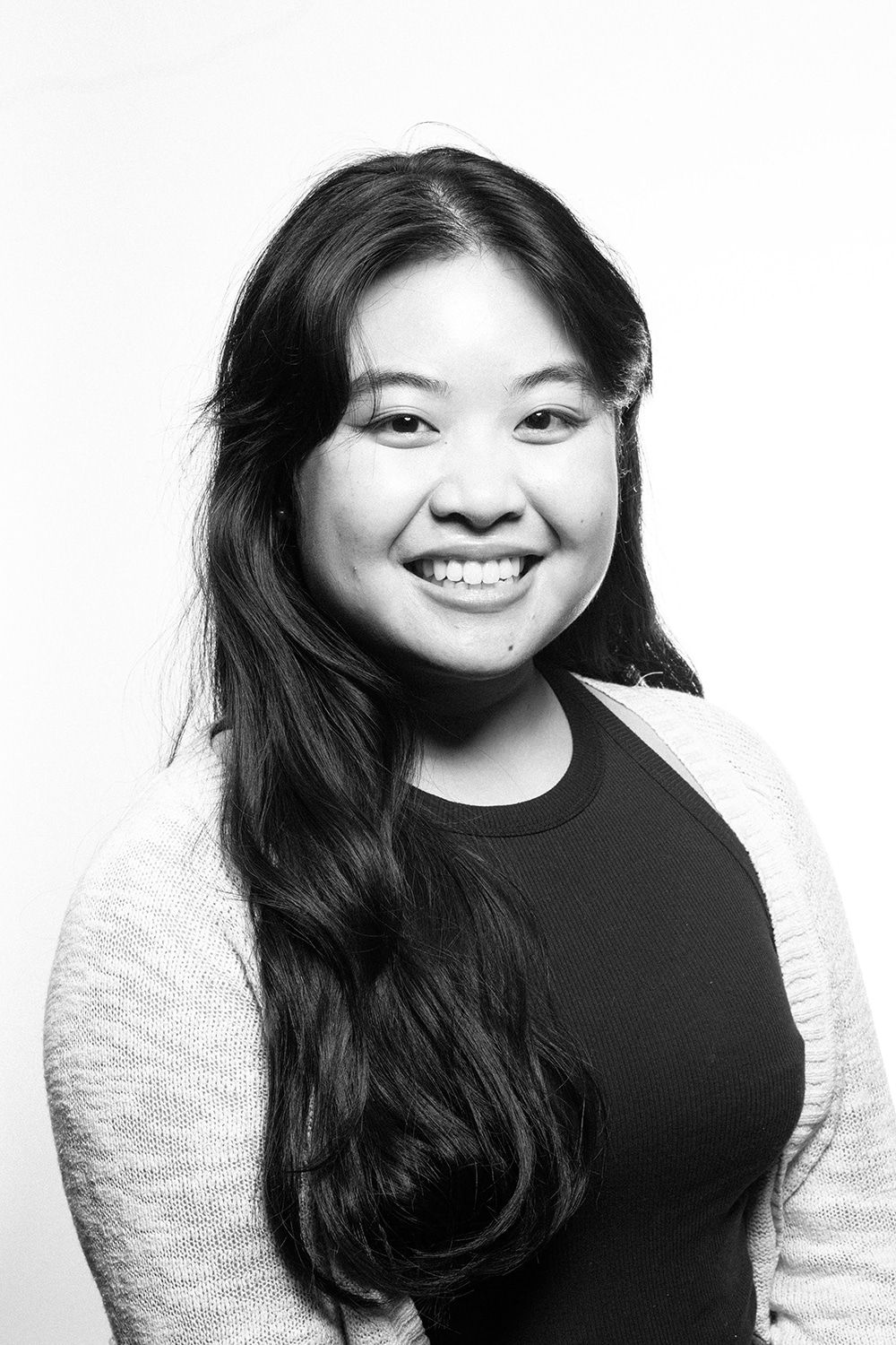 A woman with long hair is smiling in a black and white photo.
