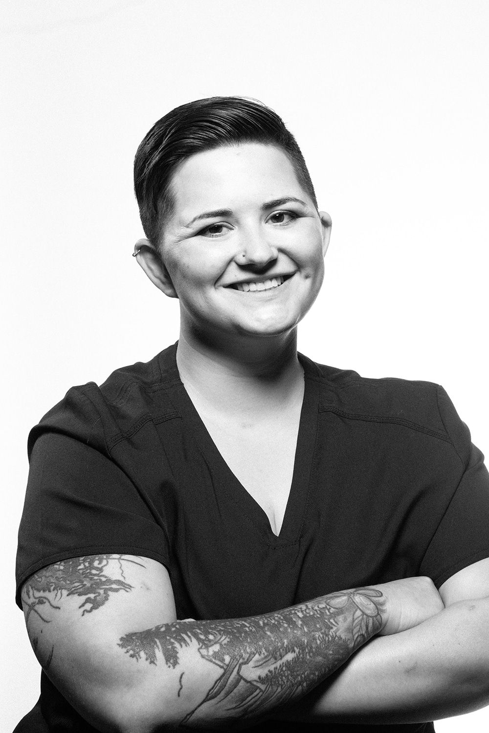 A black and white photo of a woman with tattoos on her arms.