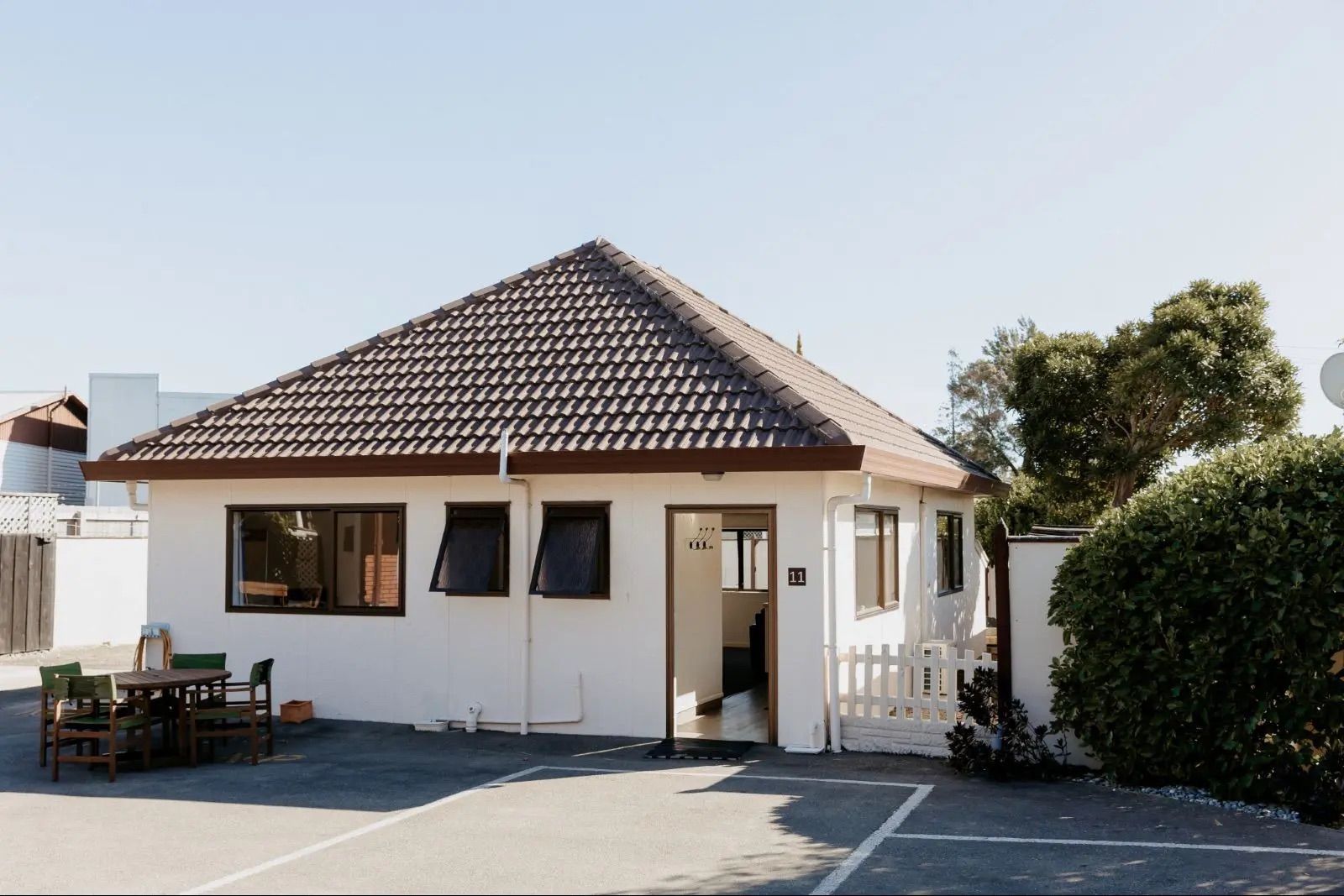 A House With Picnic Tables And Umbrellas In Front Of It — Ambercourt Motel in Robina, QLD
