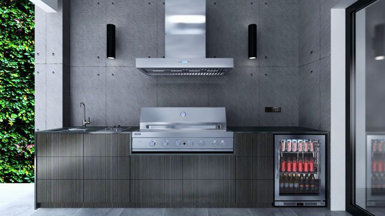 Outdoor kitchen with grill, sink, and beverage cooler against a concrete wall.