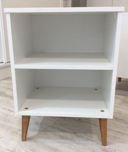 White nightstand with two shelves and angled wooden legs.