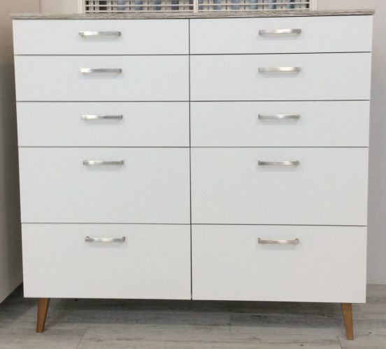 White dresser with eight drawers, silver handles, wooden legs.