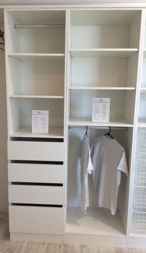 White closet organizer with shelves, drawers, and hanging rod holding a gray shirt.