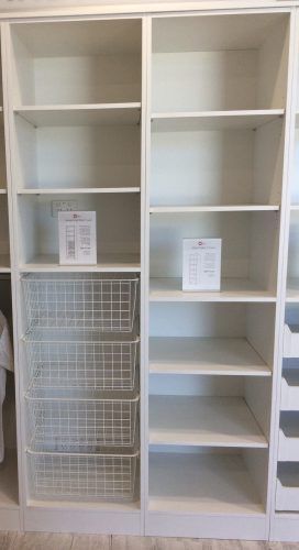 White closet shelving with empty shelves, wire basket drawers, and informational papers.