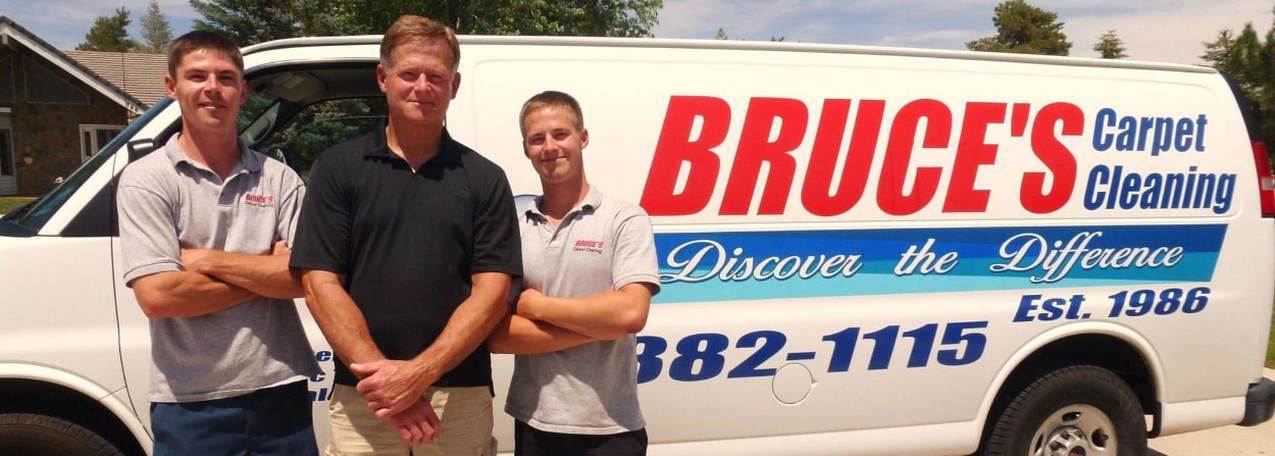 Three people standing in front of a bruce 's carpet cleaning van