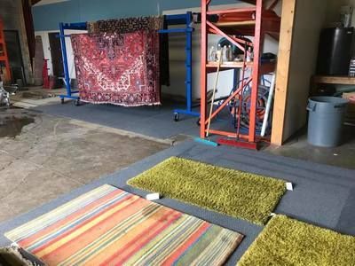 A room with a lot of rugs on the floor and a rug on a cart.