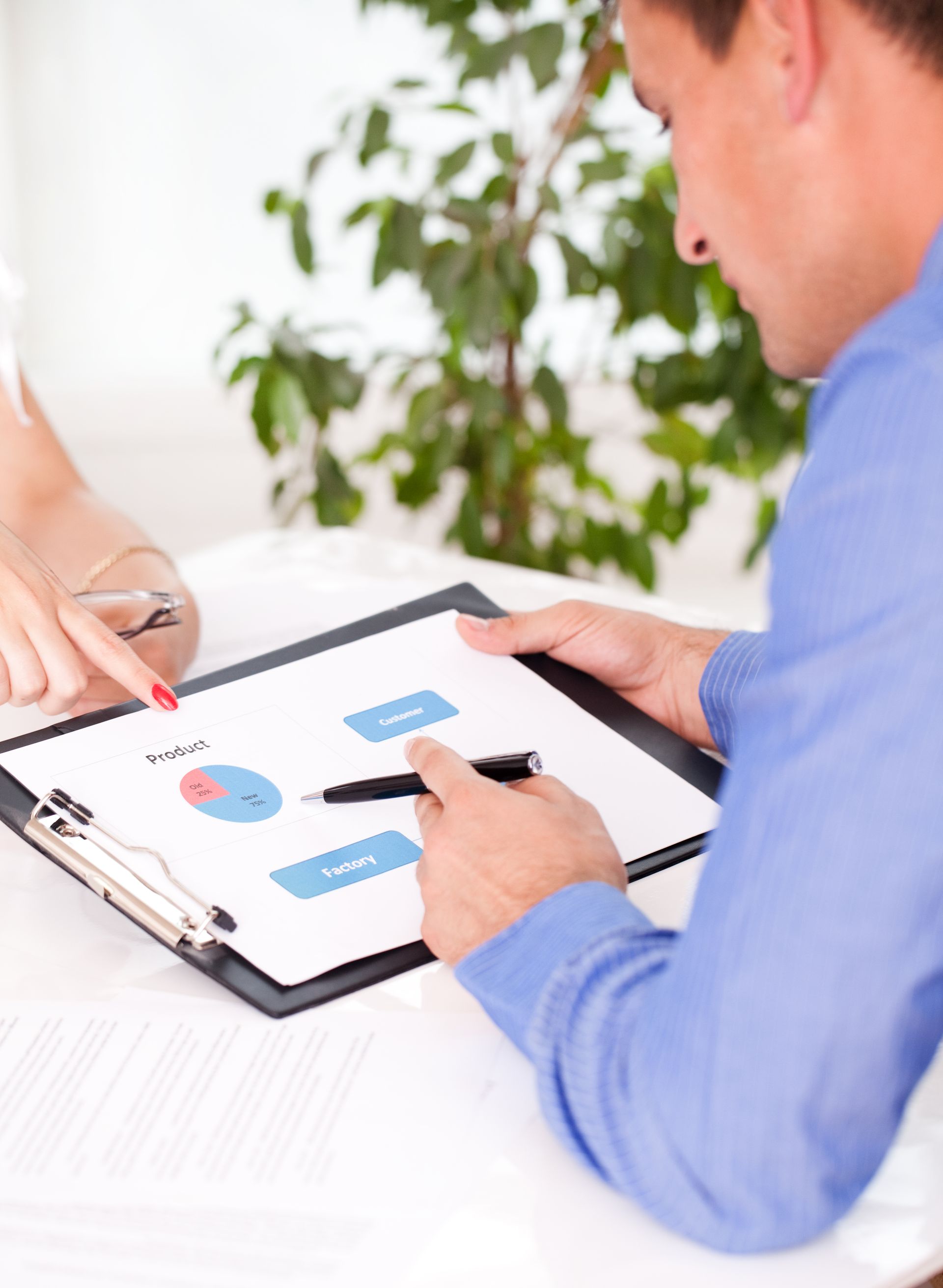 A man and a woman are looking at a clipboard with a graph on it