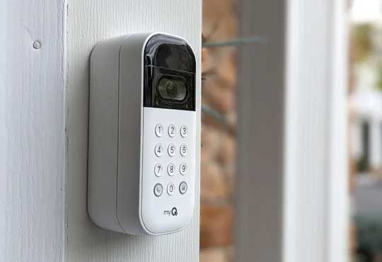 Wall-mounted keypad security lock with black screen and white buttons on a gray doorframe