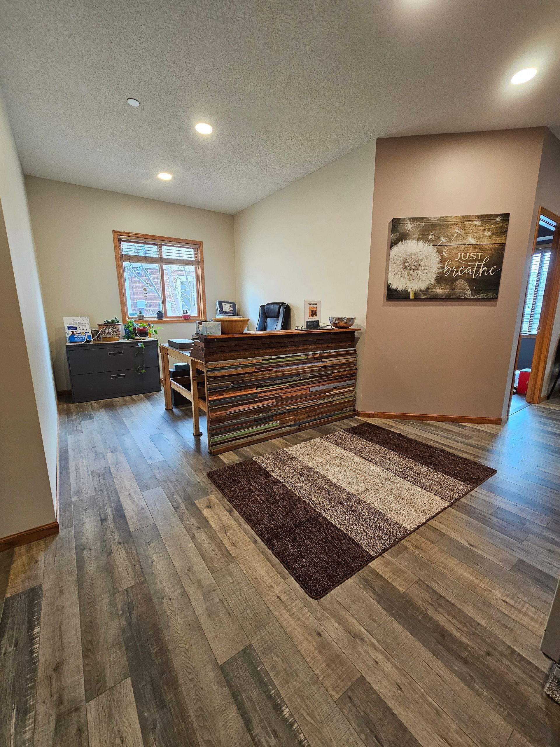 Reception area with desk, brown rug, and dandelion art.